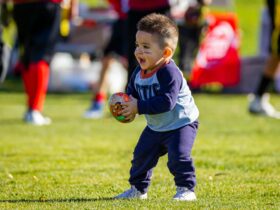 Boy in Purple Long Sleeves Shirt and Purple Pants Holding Brown Football